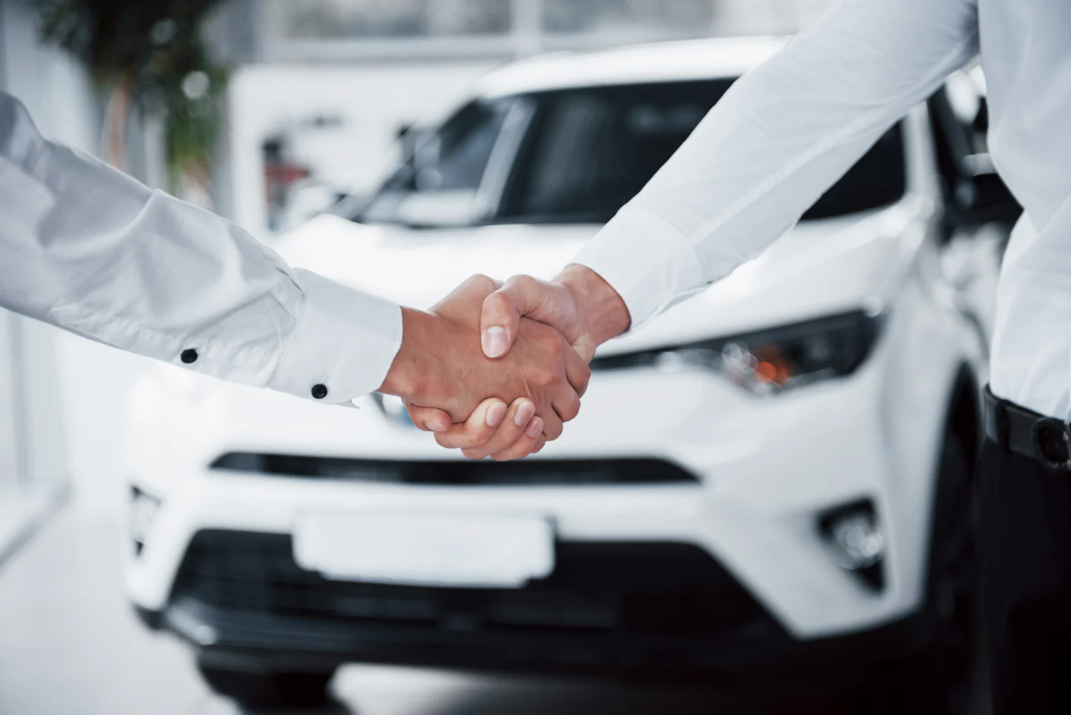 Mãos de homens se cumprimentando após ver que compensa comprar carro de leilão