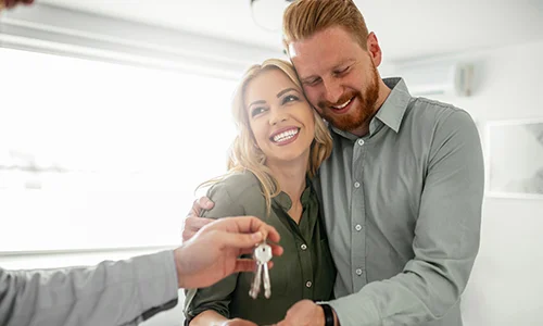 Casal feliz recebendo as chaves do seu apartamento após comprar imóvel em leilão