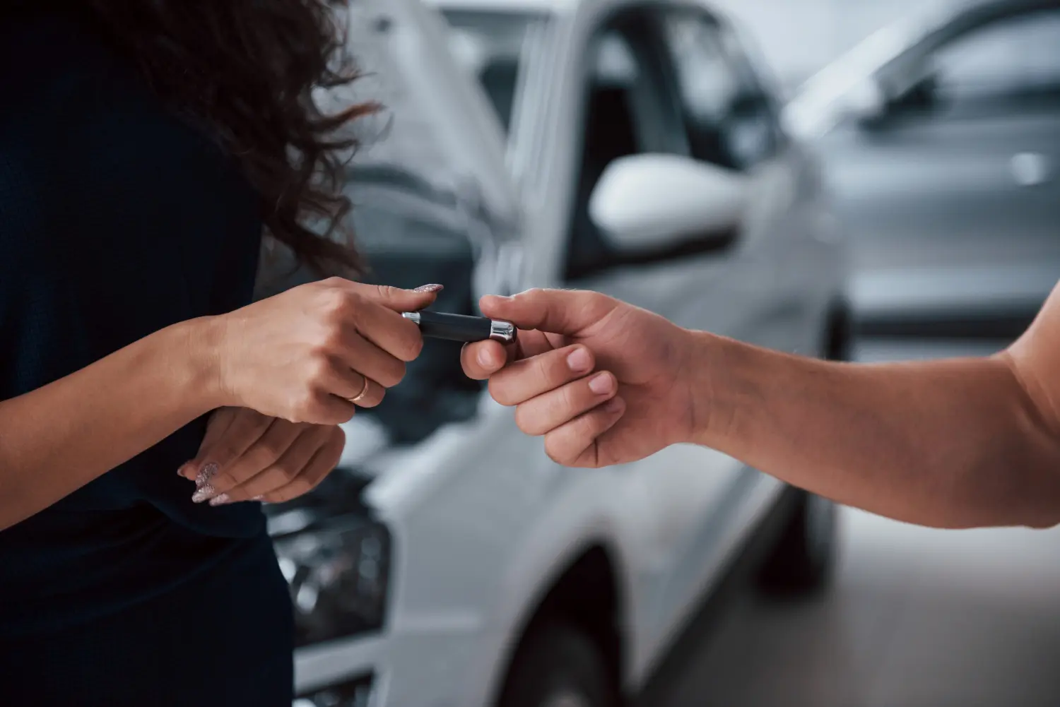 Mãos de homem entregando chave do carro para mulher após arrematar em leilão judicial de veículos